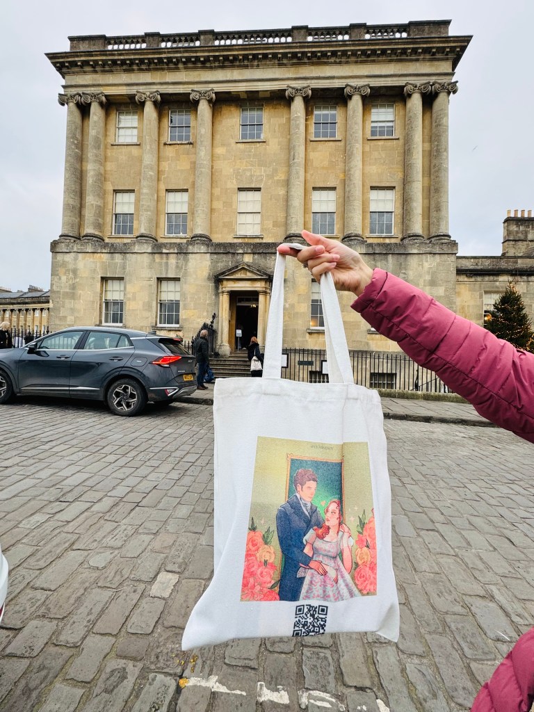 Fan holding a bridgerton polin theme tote bag infront of Royal Crescent Hotel bridgerton filming location